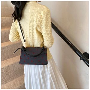 Polka dot canvas shoulder bag with black rope handle shown on a model's side view