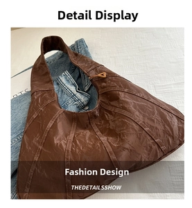 Detail of brown pleated leather hobo bag with vintage stitching and gold zip puller