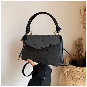 Detail of dark grey handbag with black star pattern and elegant gold ring hardware