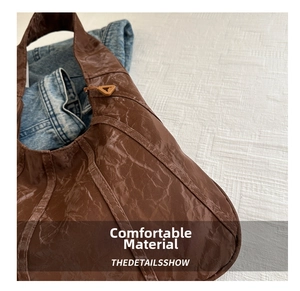 Detail of dark brown crinkled leather tote bag with stylish triangular metal zipper head