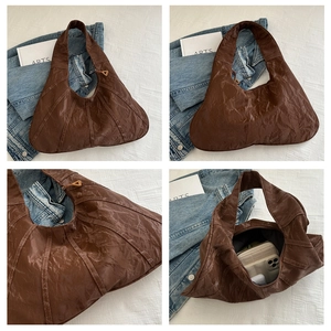 Detail view of large brown pleated shoulder bag with gold zipper and spacious interior