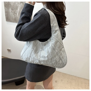 Detail of silver metallic hobo bag with pleated texture and triangular metal hardware
