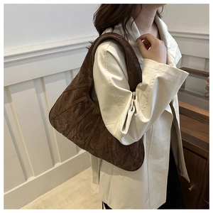 Detail of dark brown pleated tote bag with retro wrinkled texture on a beige trench coat