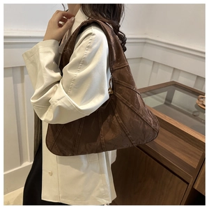 Detail of dark brown tote bag with vintage pleated texture and wide shoulder strap