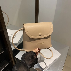 Elegant beige bucket bag with round buckle and crossbody strap for modern women