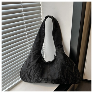 Close-up of pleated black hobo bag with stitched panels and matte textured finish