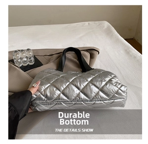 Detail of silver quilted tote bag showing high-shine fabric and diamond stitching texture