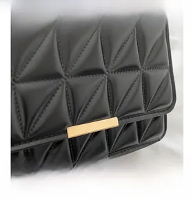 Detailed view of black quilted faux leather handbag with golden rectangular clasp