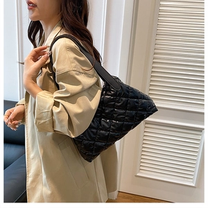 Detail view of black quilted tote bag showing padded texture and long shoulder strap