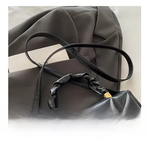 Detail of black quilted leather crossbody bag with twisted handle and gold hardware