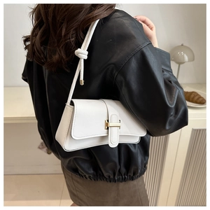 Detailed side view of white leather shoulder bag with gold buckle and knot strap detail