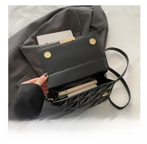 Detail of spacious interior in black quilted crossbody bag with golden hardware