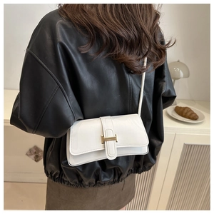 Close-up of white leather shoulder bag with a gold H-shaped buckle on model back