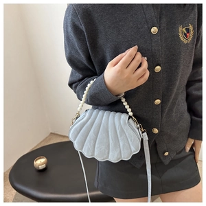 Chic shell-shaped crossbody bag featuring pearl handle and metallic blue textured leather