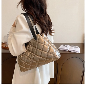 Detailed close-up of quilted champagne metallic tote bag with black leather shoulder strap