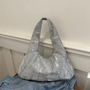 Silver large tote bag with pleated texture and metallic finish on denim background