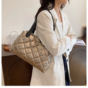 Detail of champagne gold quilted tote bag with diamond stitching and black shoulder strap