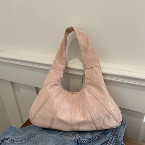 Pink pleated hobo shoulder bag with textured stitching on a casual lifestyle background
