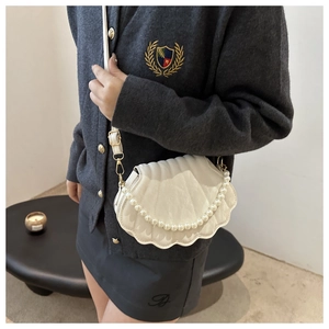 Detailed view of a white shell-shaped shoulder bag with quilted leather and pearl chain