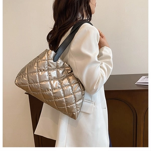 Close-up of champagne gold quilted tote bag with shiny metallic finish and black strap