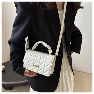 Close-up of white quilted handbag featuring triangle stitching and cloud-like pleated handle