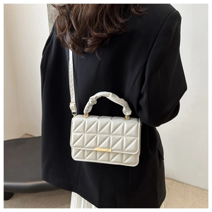 Detail of white quilted crossbody bag with unique triangular pattern and ruched handle