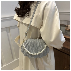 Detail of light blue shell bag with pleated silk texture and large pearl handle