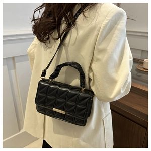 Detail of black geometric textured handbag with ruffled handle and gold metal hardware