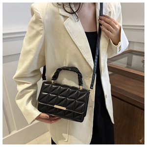 Detail of black quilted shoulder bag featuring gold buckle and ruched handle design