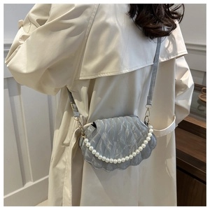 Detail of light blue shell crossbody bag with pearl chain and pleated texture