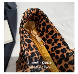 Detailed close-up of the smooth golden metal zipper on a leopard print canvas tote bag