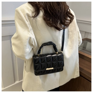 Detail of black quilted shoulder bag with gold clasp and ruched handle on model