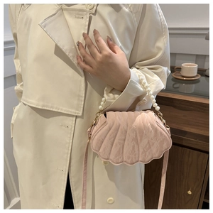 Detailed view of a pink shell-shaped crossbody bag with pearl handle and leather strap
