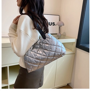 Detailed side view of silver quilted tote bag with diamond stitching on model shoulder