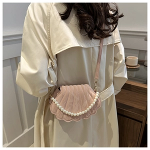 Detail of pink shell crossbody bag with radial texture and pearl handle accessory