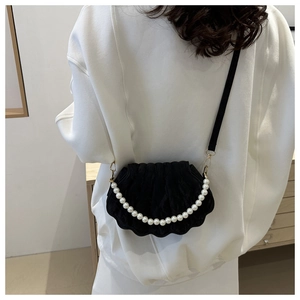 Detail of black shell-shaped velvet bag with large pearl chain and gold hardware