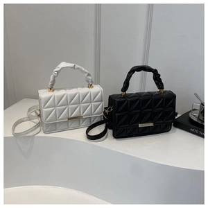 Close-up of black and white quilted crossbody bags with stylish pleated handles and gold trim