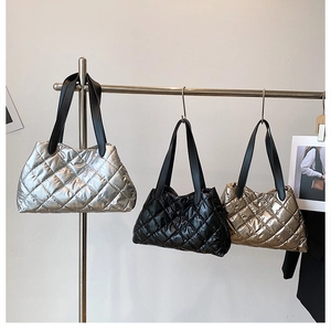 Close-up of three quilted tote bags in shiny silver, black, and champagne gold metallic finish