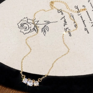 Elegante collana placcata oro con tre zirconi rotondi scintillanti su una sottile catena