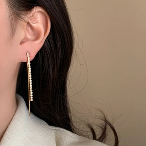Elegant gold tassel earrings with zircon crystals shown on a model in a profile view