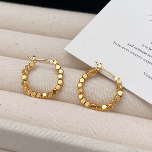 Elegant gold beaded hoop earrings in vintage style displayed on a beige jewelry tray