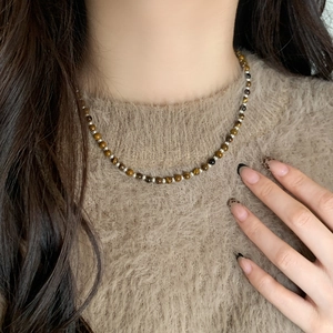 Detail of tiger eye stone beaded necklace on a brown sweater for autumn style