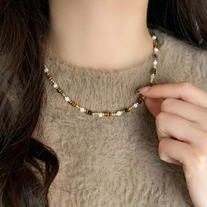 Detail of natural stone and shell beaded necklace on a brown sweater background
