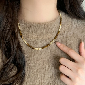 Handmade tiger eye stone and shell beaded necklace with gold metal accents on a model