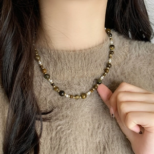 Handmade tiger eye stone and pearl beaded necklace on brown knit sweater background
