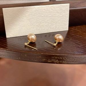 Elegant champagne gold pearl drop earrings with glossy finish on a wooden surface