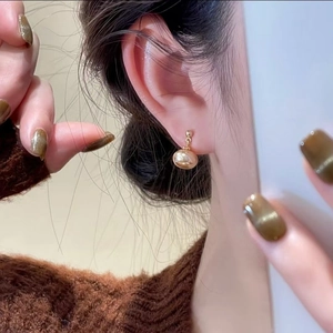 Elegant champagne gold pearl stud earrings worn by a model in a close-up lifestyle shot