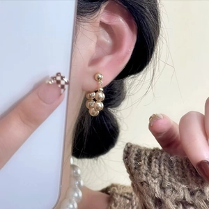 Eleganti orecchini a cerchio con perle dorate champagne indossati da una modella con maglione