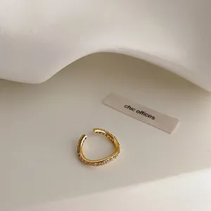 Élégante bague d'oreille plaquée or avec zircons brillants sur un fond blanc épuré