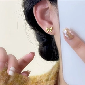 Élégantes boucles d'oreilles nœud papillon doré champagne mat portées par un modèle